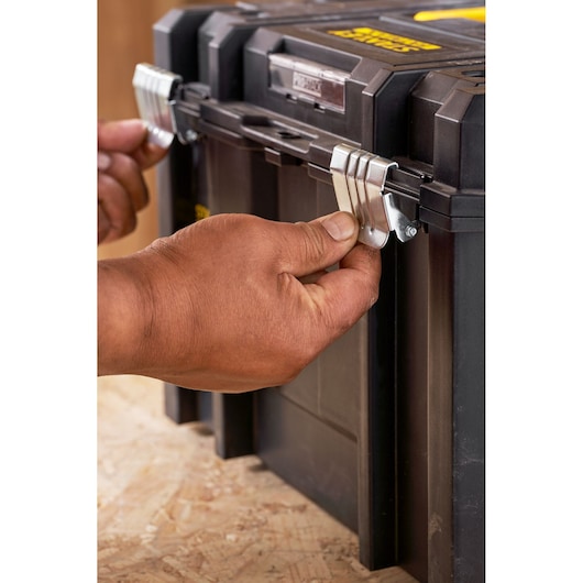 STANLEY FMST1-71971 toolbox front angle, hands securing metal latches on black storage box.