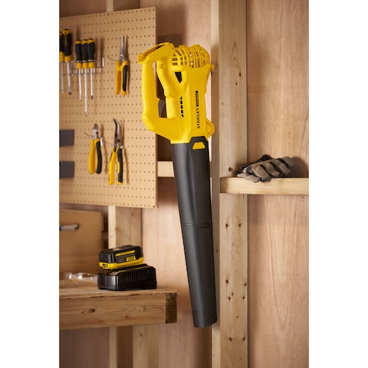STANLEY SFMCBL714M1 cordless leaf blower with battery pack in a workshop setting, side angle.