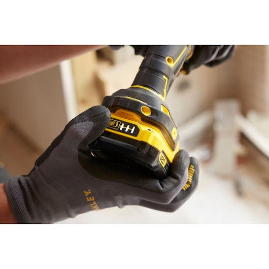 STANLEY SFMCD710C2K cordless drill held by gloved hand, close-up view showing yellow and black design.