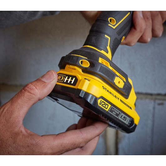 Stanley SFMCD715C2K V20 cordless drill close-up with hand holding yellow and black grip and battery.