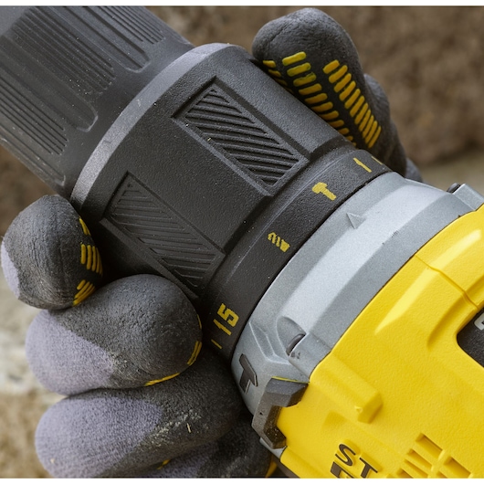 Photo of STANLEY SFMCD715C2K drill, close-up of hand adjusting torque settings, yellow and black casing.