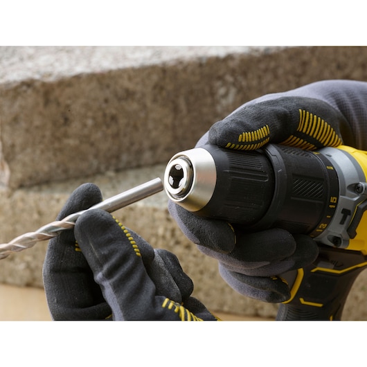 Photo of STANLEY SFMCD715M12 cordless drill, close-up side view, gloved hands inserting a drill bit.