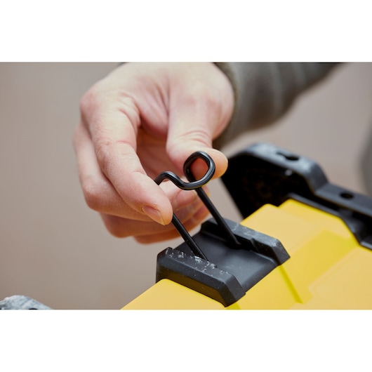 STANLEY SFMCE001B close-up of hand using black metal latch on yellow product surface.