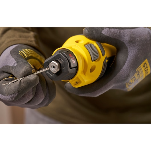 Stanley SFMCE200B rotary tool held in gloved hand with tool bit being inserted, close-up angle.