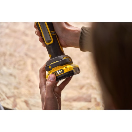 Photo of STANLEY SFMCE510B cordless sander held in hands, close-up view of handle and battery.
