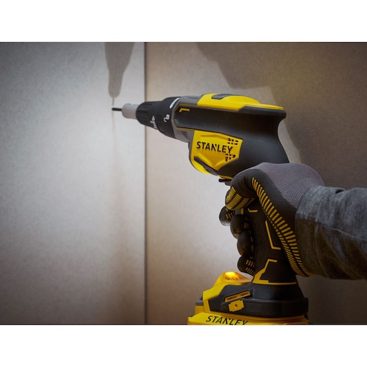 Photo of STANLEY SFMCF600B cordless screwdriver used on drywall, side angle view.