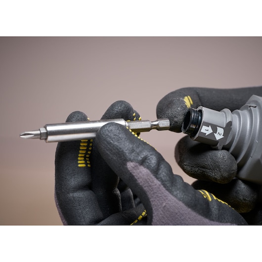 STANLEY SFMCF600B photography of drill bit insertion with gloved hands close-up.