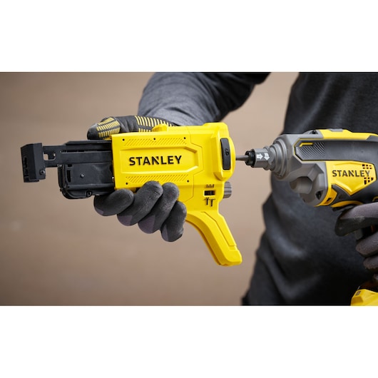 Photo of STANLEY SFMCF600B fastener tool in hand, close-up view with grey and yellow color details.