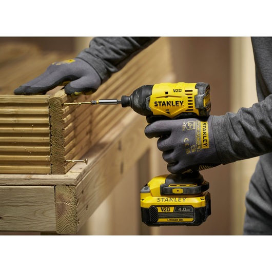 Stanley V20 cordless impact driver used to drill screws into wooden boards in a construction setting.