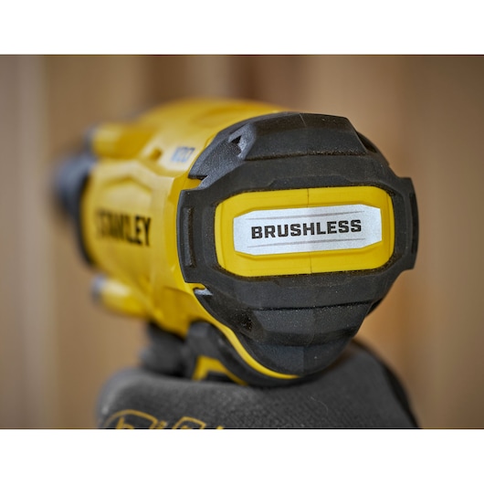 Close-up of a STANLEY brushless power tool held in a gloved hand, showing the 'BRUSHLESS' label.