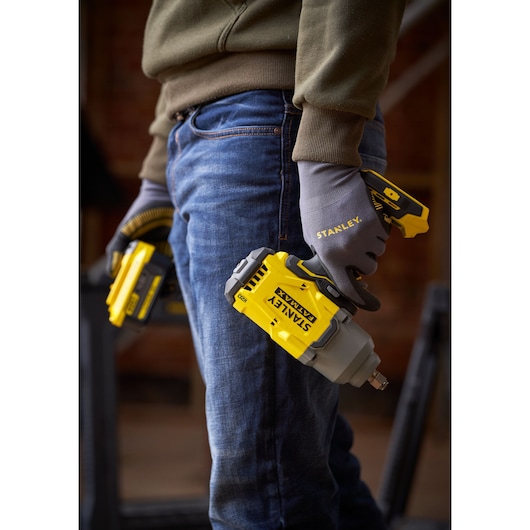 Photo of STANLEY SFMCF940M1 cordless impact wrench held by a gloved hand, showing yellow and gray design.