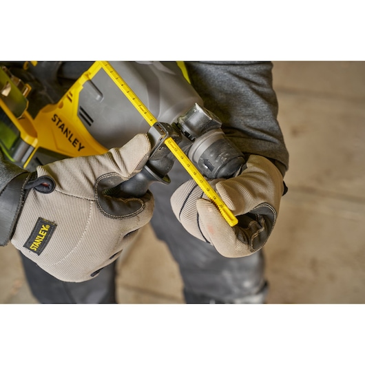 Photo of STANLEY SFMCH910B rotary hammer drill being adjusted by gloved hands, close-up angle.