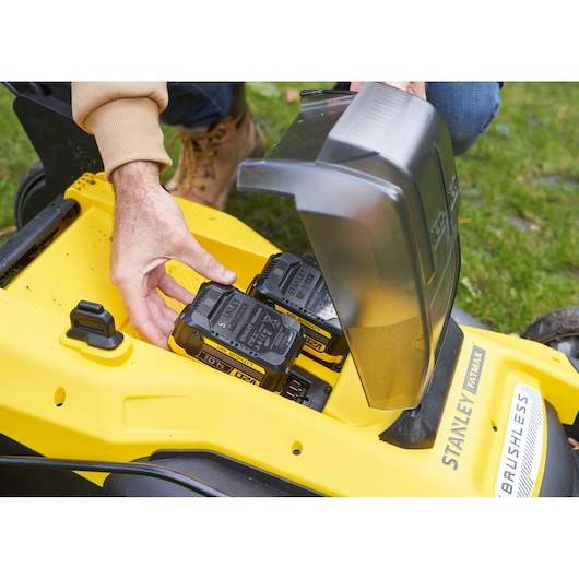 Photo of STANLEY SFMCMWS251M lawn mower battery compartment with two batteries being inserted.