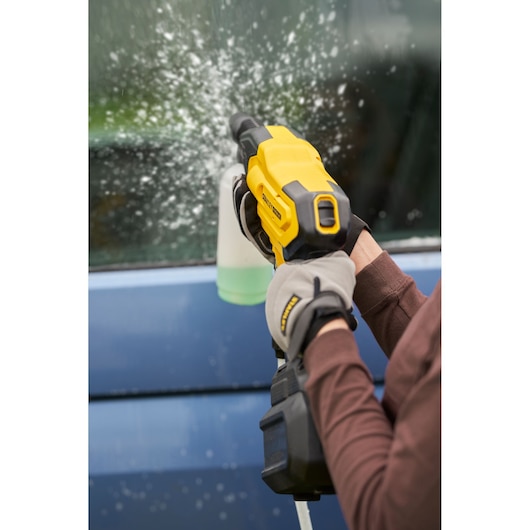 STANLEY SFMCPC93B handheld power cleaner spraying water on a car window, close-up photo.
