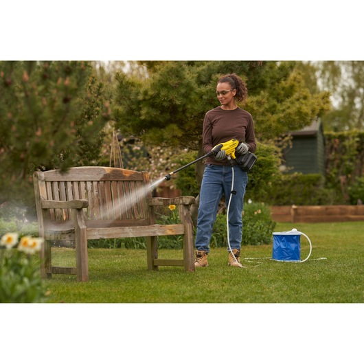 STANLEY SFMCPC93M1 pressure washer in use cleaning a wooden bench outdoors, garden setting.