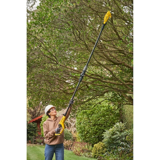 STANLEY SFMCPP632D1 pole saw used outdoors for tree trimming, yellow and black design, photography.