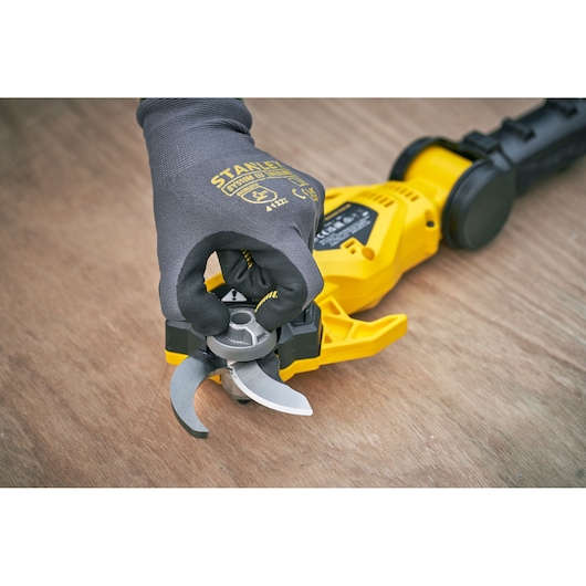 Photo of STANLEY SFMCPP632D1 cordless pruner with close-up of gloved hand adjusting silver blades.