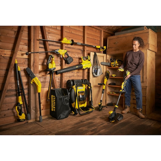 STANLEY SFMCPS620M1 garden power tool kit displayed with tools hung and stored in wooden shed.