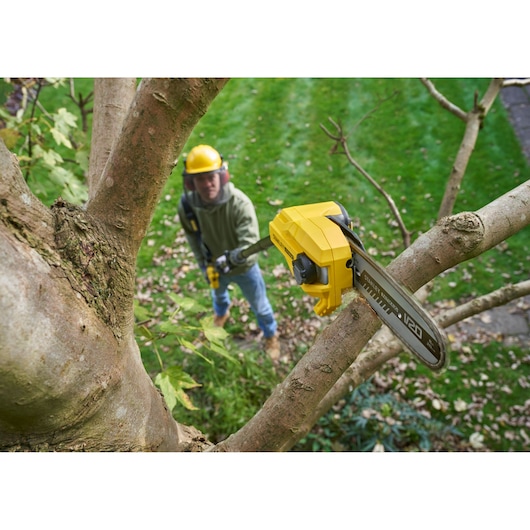 STANLEY SFMCPS720M1 pole saw trimming tree branch outdoors, close-up of saw blade cutting wood.