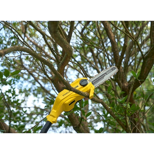 STANLEY SFMCPS720M1 yellow pole saw trimming tree branches outdoors, close-up photography.