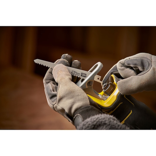 Photo of STANLEY SFMCS310B reciprocating saw blade being installed, close-up of hands wearing work gloves.