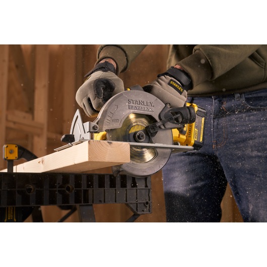 STANLEY SFMCS500B circular saw cutting wood, close-up side angle, worker wearing gloves.