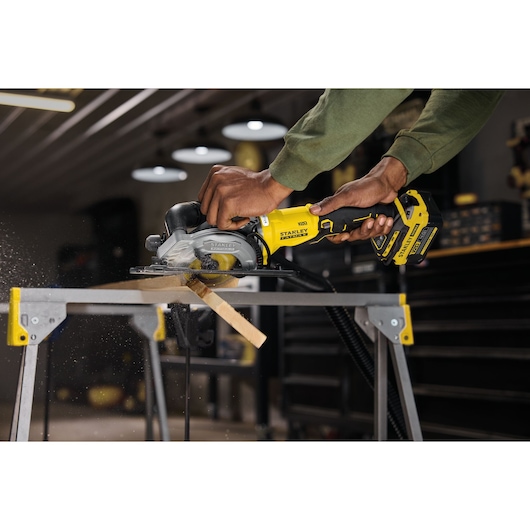 STANLEY SFMCS515B cordless circular saw cutting wood on a workbench in workshop.