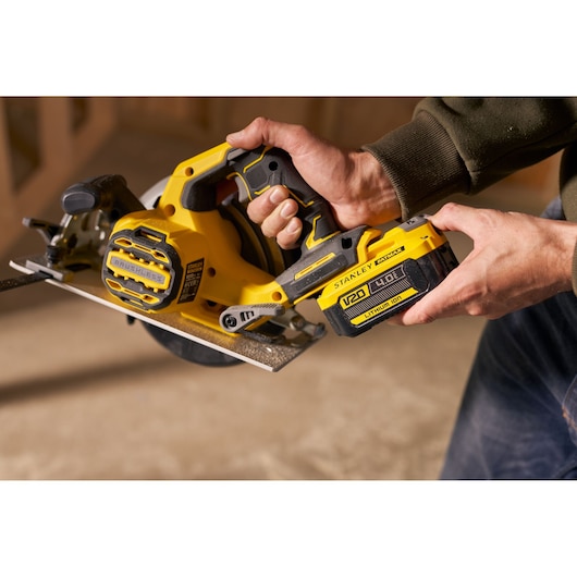 Photo of STANLEY SFMCS550B brushless cordless circular saw being held, yellow and black body, woodworking.