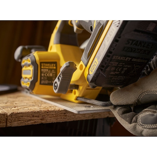 Photo of STANLEY SFMCS550B cordless jigsaw cutting wood, close-up angle showing battery and grip.