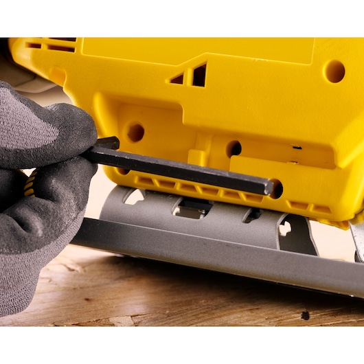 STANLEY SFMCS600B jigsaw adjustment with hex key, close-up photo of yellow body and gray metal base.