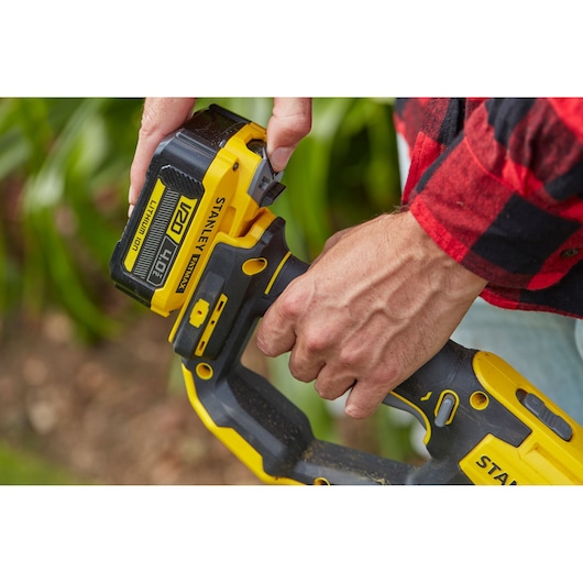 Photo of STANLEY SFMCST933M1 V20 Lithium-Ion tool, close-up of battery being attached outdoors.