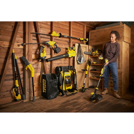 STANLEY SFMCSTB933B garden power tools kit in shed, multiple yellow tools arranged with bag and backpack.