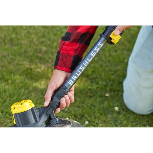 Stanley SFMCSTB933M brushless string trimmer with yellow battery, close-up on grass.