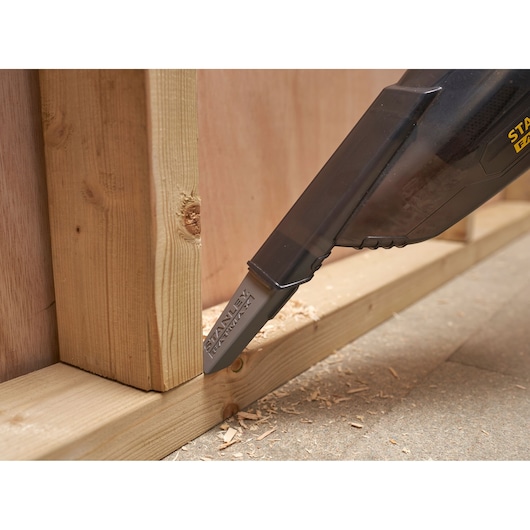 STANLEY SFMCVH001B handheld vacuum cleaning wood shavings on floor near wooden frame, close-up angle.