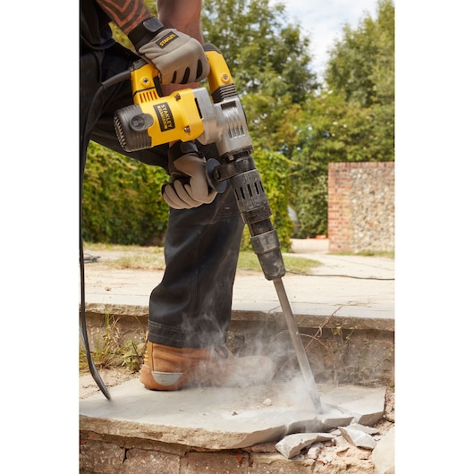 STANLEY SFMEH220K-QS rotary hammer breaking concrete outdoors, close-up view of tool in use.