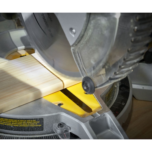 STANLEY SM1650 miter saw cutting wood, close-up angle, yellow insert and blade visible.