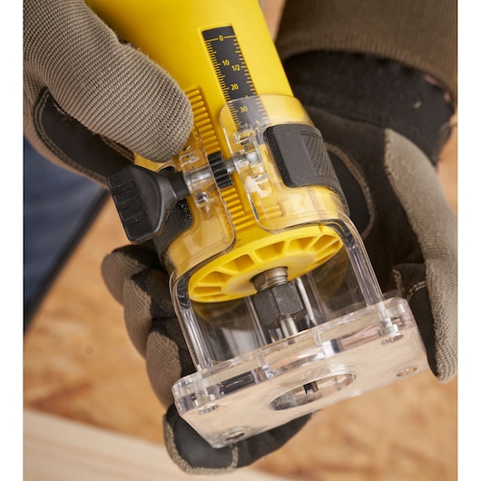Photo of STANLEY ST55 power tool being adjusted by gloved hands, close-up on depth gauge and transparent base.