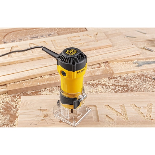 Stanley ST55-KR photography of yellow wood router on carved wooden board, showing tool in use.