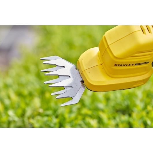 STANLEY STCSS20D1 garden shear close-up, yellow body and steel blades, outdoors with greenery.