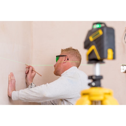 Photo of STANLEY STHT1-77367 laser level projecting green line, used by person marking wall, photography category.