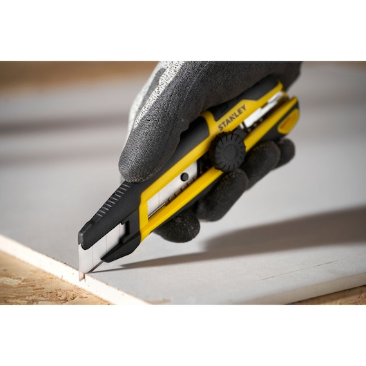 Photo of STANLEY STHT10500-0 utility knife with yellow and black handle cutting drywall.