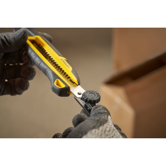 STANLEY STHT10500-0 utility knife with yellow and black handle in use, close-up photo.
