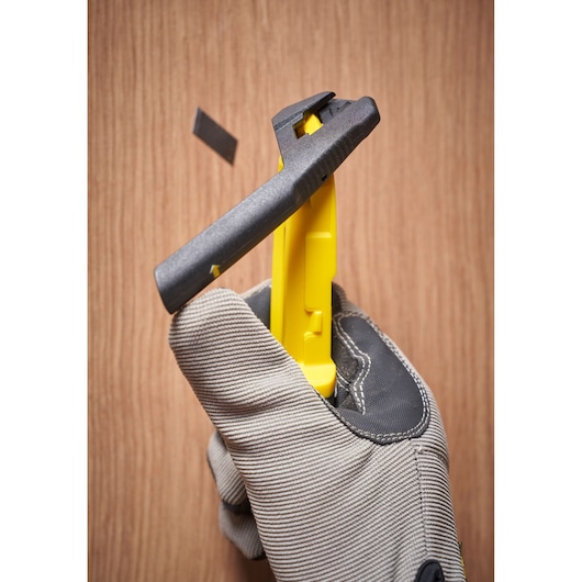 STANLEY STHT10501-0 utility knife in yellow and black held in gloved hand, blade ejecting, close-up photo.