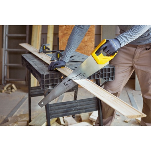 STANLEY STHT20350-1 hand saw with yellow handle cutting wood plank in workshop, photography category.