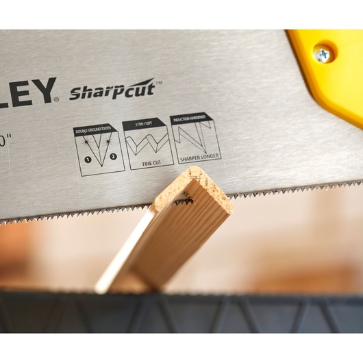 STANLEY STHT20371-1 hand saw blade with SharpCut teeth cutting a wooden plank, close-up photo.