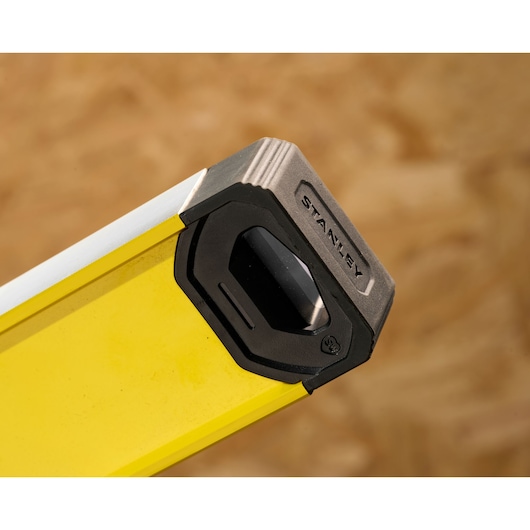 Close-up of the end of a yellow Stanley spirit level with protective black and grey cap.