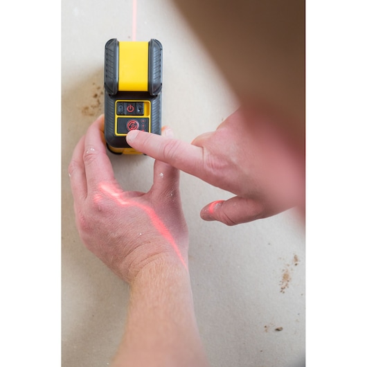 Photo of STANLEY STHT77504-1 laser level tool, top view, in use with visible red laser line on a flat surface.