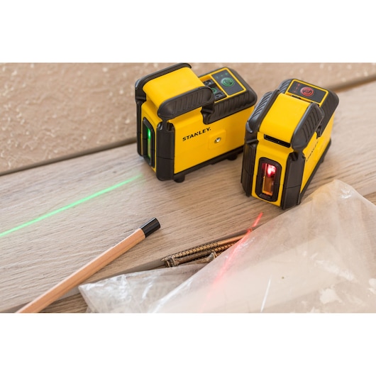 STANLEY STHT77504-1 laser level tools with green and red beams on wood surface, pencil and screws nearby.