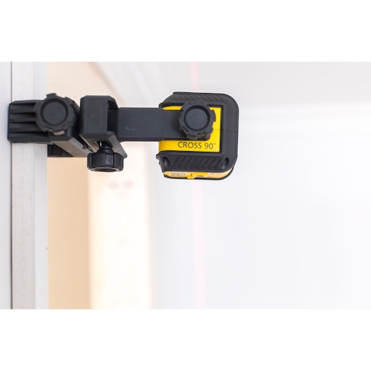 STANLEY STHT77592-1 cross line laser level mounted on wall, side angle, yellow and black body.
