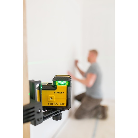 Photo of STANLEY STHT77594-1 Cross 360° laser level mounted on a clamp, projecting green line in a room.
